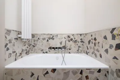 a white bath tub in a bathroom with tiles at Modern apartment in the heart of the Old Town in Kraków