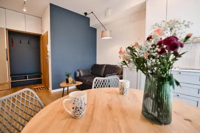 a vase of flowers on a wooden table with two cups at Flower Blue 2 by Housine in Zator