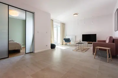 a living room with a large mirror and a bedroom at Przestronny apartament PARKING by NEARTOpl in Kraków