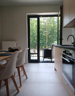 a kitchen with a table and chairs and an open door at Apartament Parkowa 8 in Myślenice