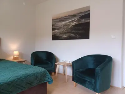 a bedroom with two green chairs and a bed at Apartament Parkowa 8 in Myślenice