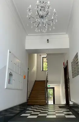 a hallway with a chandelier and a staircase at Premium Black Apartment Krakow Center with Parking in Kraków
