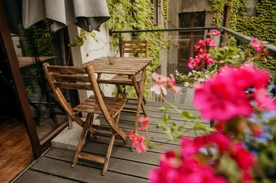 a wooden table and chair on a balcony with pink flowers at Premium Black Apartment Krakow Center with Parking in Kraków