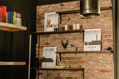 a brick wall with shelves and books at Premium Black Apartment Krakow Center with Parking in Kraków