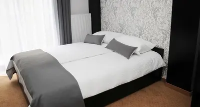 a bedroom with a large bed with white sheets and pillows at Hotel Klaudia in Juszczyn