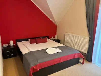 a bedroom with a bed with a red wall at Hotel Klaudia in Juszczyn