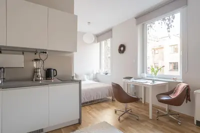 a white kitchen with a bed and a desk and chairs at Quiet Studio in the heart of Kazimierz AC in Kraków
