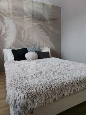 a bedroom with a white bed with a feather painting on the wall at Wieliczka4You in Wieliczka