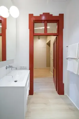 a bathroom with a white sink and a red door at lovely place, modern design, historic townhouse in Kraków