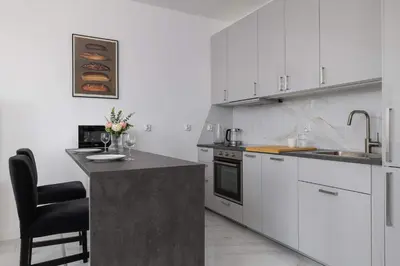 a kitchen with white cabinets and a sink and a counter at Fabryczna Modern Apartment with Balcony & Parking in Cracow by Noclegi Renters in Kraków