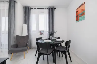 a dining room with a black table and chairs at Fabryczna Modern Apartment with Balcony & Parking in Cracow by Noclegi Renters in Kraków