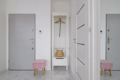 a hallway with two pink chairs and a vase on a shelf at Fabryczna Modern Apartment with Balcony & Parking in Cracow by Noclegi Renters in Kraków