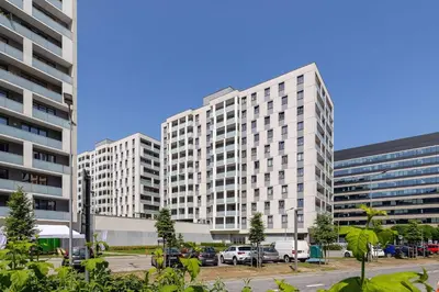two tall white buildings in a parking lot at Fabryczna Modern Apartment with Balcony & Parking in Cracow by Noclegi Renters in Kraków