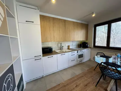 a kitchen with white cabinets and a table in it at Mon Rêve in Kraków