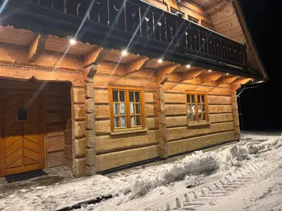 a wooden cabin in the snow with lights on it at Mecenasówka in Zawoja