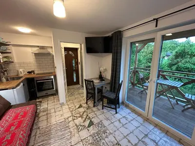 a living room with a table and a kitchen with a balcony at W górach nad strumieniem in Bieńkówka