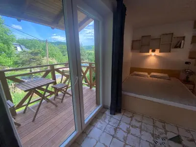 a bedroom with a bed and a balcony with a table at W górach nad strumieniem in Bieńkówka