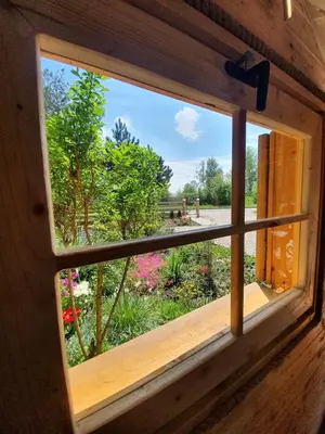 a window with a view of a garden with flowers at Sosnowy Domek in Zator