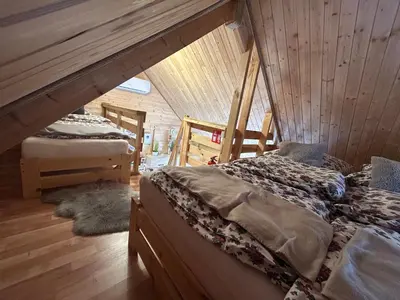 two beds in a room with wooden walls at Sosnowy Domek in Zator