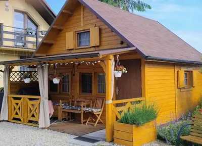 a wooden house with a table and a porch at Sosnowy Domek in Zator