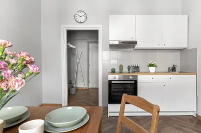 a kitchen with white cabinets and a table and a clock at ANTA Apartments Warszawska in Kraków