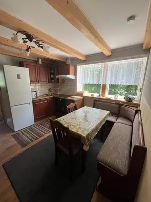 a kitchen with a table and a couch and a refrigerator at Dom pod Świerczkiem in Słopnice
