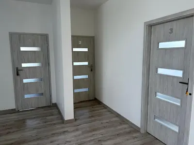 two doors in an empty room with wooden floors at AP Apartament in Kraków