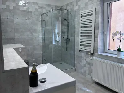 a bathroom with a sink and a glass shower at AP Apartament in Kraków