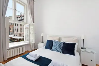 a bedroom with a bed with blue pillows and a window at Spacious Apartment in Krakow Old Town in Kraków