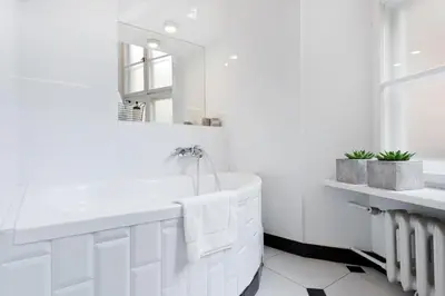 a white bathroom with a tub and a mirror at Spacious Apartment in Krakow Old Town in Kraków