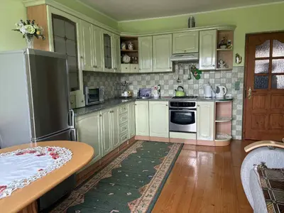 a kitchen with white cabinets and a table in it at Noclegi w Beskidzie Wyspowym in Przenosza