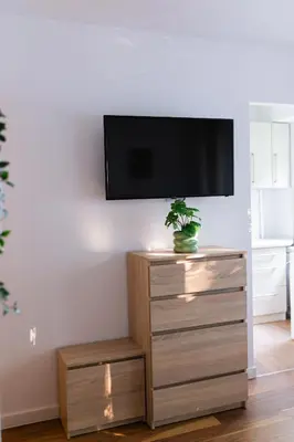 a flat screen tv on a wall above a dresser at Przytulny Apartament w centrum Rabki in Rabka