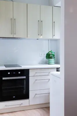a kitchen with white cabinets and a black oven at Przytulny Apartament w centrum Rabki in Rabka