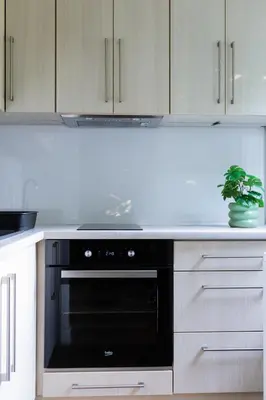 a kitchen with a black oven and white cabinets at Przytulny Apartament w centrum Rabki in Rabka