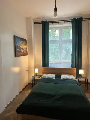 a bedroom with a large green bed with a window at City Center Rooms in Kraków