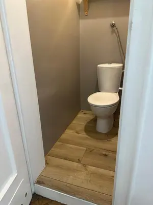 a bathroom with a toilet and a wooden floor at City Center Rooms in Kraków