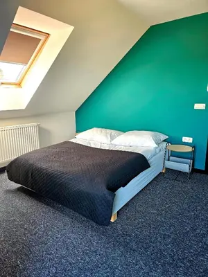 a bedroom with a bed and a green wall at Willa za Zeliną