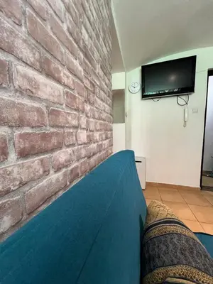 a room with a brick wall with a bed and a tv at Kawalerka-Studio underground in Kraków