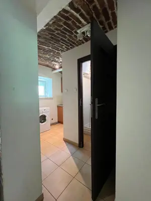 a hallway with a black door and a brick ceiling at Kawalerka-Studio underground in Kraków