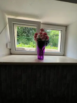 a vase of pink flowers sitting on a window sill at Kawalerka-Studio underground in Kraków
