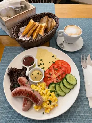 a plate of breakfast food with sausage eggs cheese and bread at Apartments Roman in Kraków