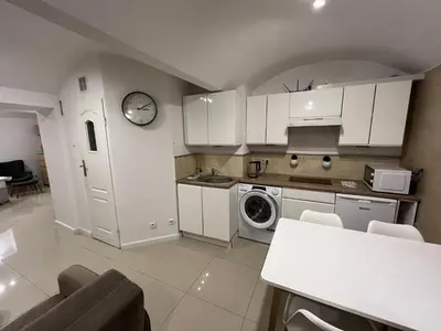 a kitchen with white cabinets and a clock on the wall at A&J Apartments in Kraków
