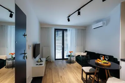a living room with a black couch and a table at Malila Premium Apartments Cracow Limanowskiego 37 in Kraków