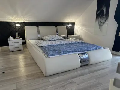 a large white bed in a room with wooden floors at Rooms near Balice airport in Cholerzyn