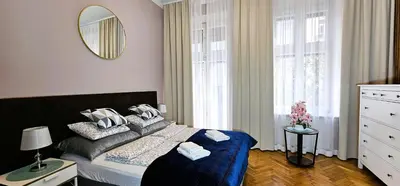 a bedroom with a bed and a mirror and windows at Old Town KRAKÓW STUDIO in Kraków