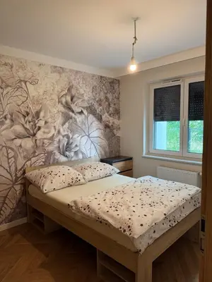 a bedroom with a bed with a flower mural on the wall at Mieszkanie do wynajęcia Rydlówka Kraków in Kraków