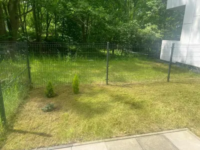 a fence in a yard with two plants at Mieszkanie do wynajęcia Rydlówka Kraków in Kraków