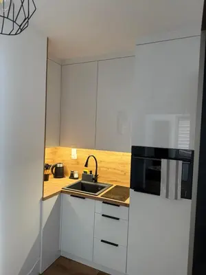 a white kitchen with a sink and a microwave at Apartament Grojec in Grojec