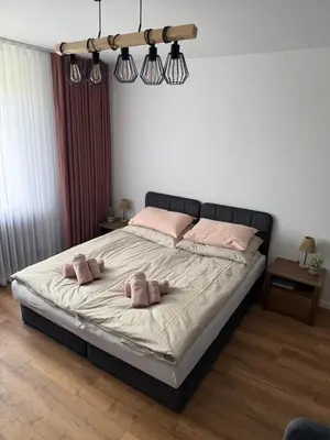 a bedroom with a large bed with pink pillows on it at Apartament Grojec in Grojec