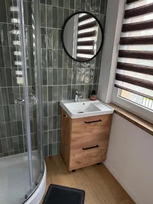 a bathroom with a sink and a shower and a mirror at Apartament Grojec in Grojec